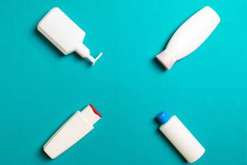 Set of White Cosmetic containers isolated on colored background, top view with copy space. Group of plastic bodycare bottle containers with empty space for you design