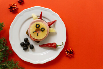 Funny sandwich with sausage, pineapple and vegetables in the shape of a bull. Festive breakfast or lunch for kids. Symbol of the new year 2021