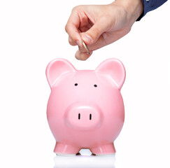 Female hand putting coin into a piggy bank on white background