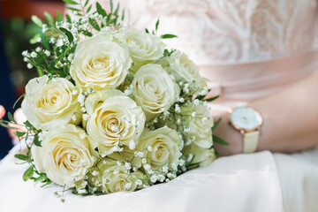 Beautiful bouquet of delicate white roses in the hands of the bride close up