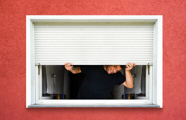 man with hands holds sunblind on pvc window