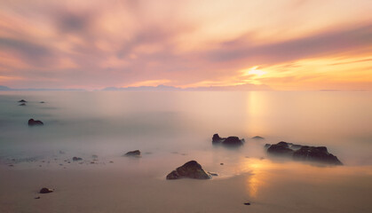 Long exposure of calm, still ocean with a pastel sunset