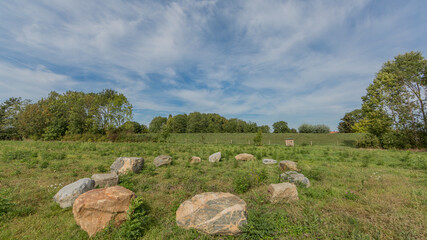 Large stones form a circle between the Dutch countryside with lush trees in the background, sunny...