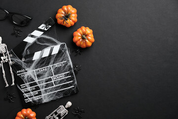Movie clapperboard and halloween decoration on black table. Horror movie night, halloween party...