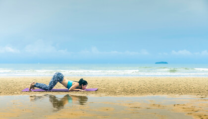 Adult Asian woman doing yoga on beach