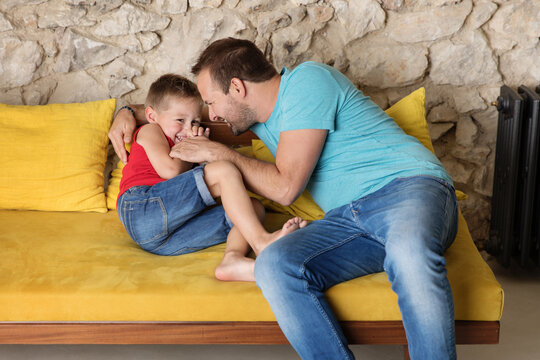 Father and son playing and laughing together on sofa
