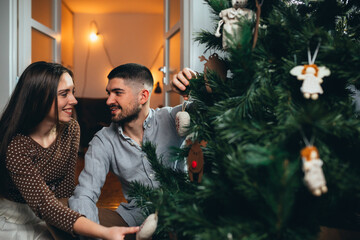 romantic couple decorating christmas tree and new yeas gifts at home