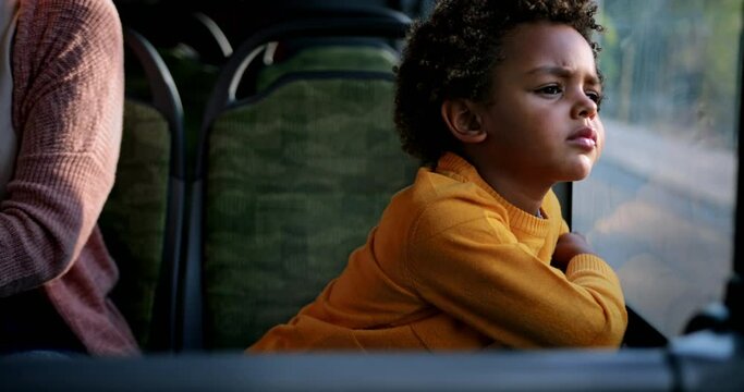 African-american young boy looking out the window inside public bus
