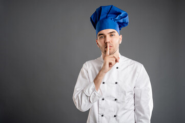 Young male dressed in a white chef suit showing shh gesture