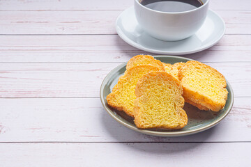 Crispy butter toast and a white coffee cup on wooden table with space for text