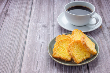 Crispy butter toast and a white coffee cup on wooden table with space for text