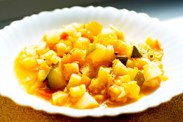 Mix of stewed vegetables on a white plate in cafe. Cooked vegan or vegetarian food.