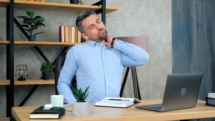 Tired man massages neck after using laptop computer long time, poor posture requiring treatment....