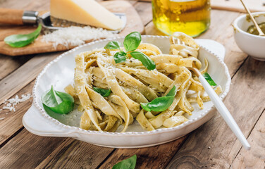 Tagliatelle pasta with pesto sauce and basil leafs.