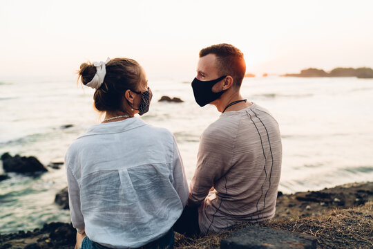 Loving couple in face masks on beach