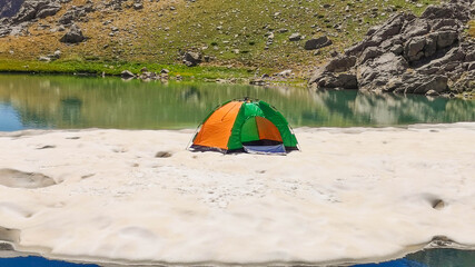 Camping tent and lake on ice floe, blue sky
