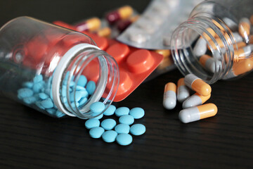 Pills and capsules on dark wooden table, a lot of multicolored medication close-up. Concept of...