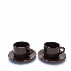 Two porcelain coffee cups and saucers stand side by side. The dishes are brown. Side view. Isolated over white background.