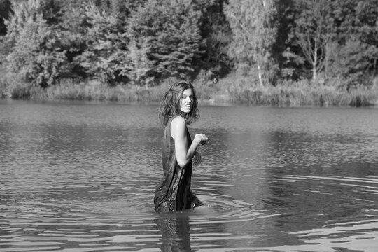 young girl in a wet dress in the lake in black and white