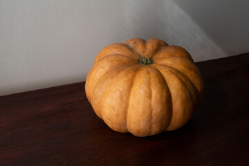 flattened orange pumpkin lies on a dark wooden background