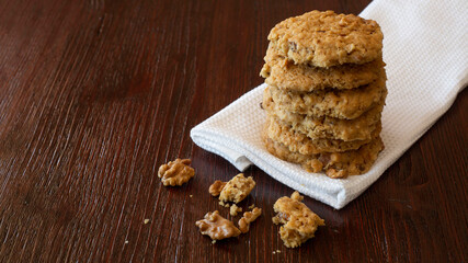 oatmeal cookies with walnuts lie in a stack on a kitchen towel on a wooden table