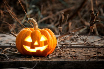 Jack-o'-lantern glowing halloween pumpkin head have yellow light on the old wood floor at abandoned...
