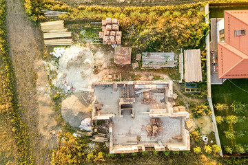 Top down aerial view of a house under construction with concrete foundament and brick walls.