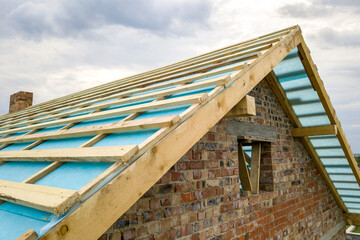 Obraz premium Aerial view of a brick house with wooden roof frame under construction.