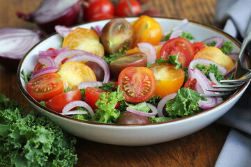 Fresh green salad with cherry tomatoes, cabbage Kale, onions on cutting board. Wooden background