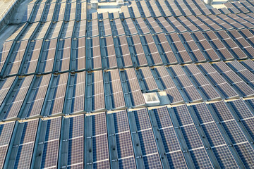 Aerial view of many photo voltaic solar panels mounted of industrial building roof.