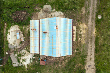 Top down aerial view of a brick house with wooden roof frame under construction.