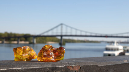 The yellow-orange  natural pieces of Baltic amber shimmering in the sun lies on an iron parapet...
