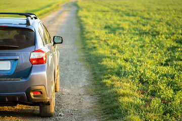 Landscape with blue off road car on gravel road. Traveling by auto, adventure in wildlife, expedition or extreme travel on a SUV automobile. Offroad 4x4 vehicle in field at sunrise. © bilanol