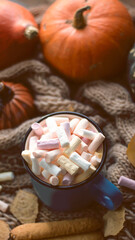 Autumn background with dry leaves, blue cup of coffee. Knitted background, pumpkins, October, November. Autumnal atmosphere. Autumn season.