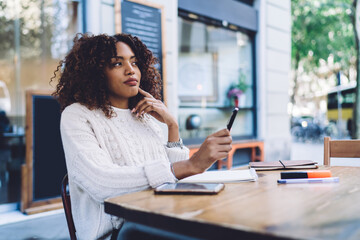 Focused black woman taking notes in planner