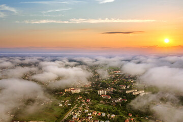Sunset over rural area in town with clouds and yellow sun.
