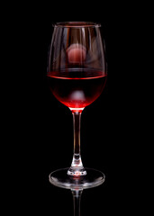 Rose wine in a glass on mirror surface isolated on black