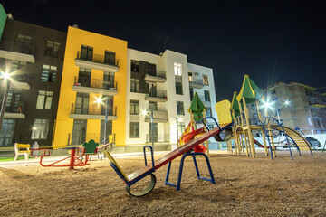 Children playground at night in residential district yard between apartment buildings.