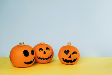 Little pumpkins with painted faces for Halloween on yellow and blue background