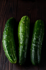 Macro photo of ripe cucumbers on dark wooden kitchen table, above view