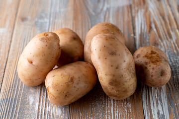 Raw unpeeled potatoes on light wooden table