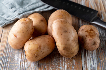 Raw unpeeled potatoes on light wooden table
