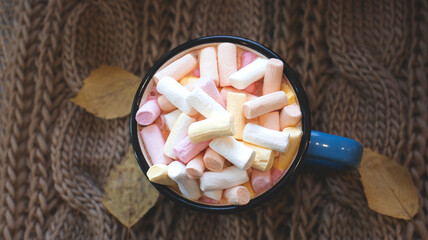 Autumn background with dry leaves, blue cup of coffee. Knitted background, pumpkins, October, November. Autumnal atmosphere. Autumn season.