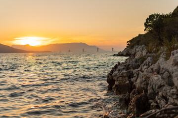 Sunset over mountains and sea. Construction site in the distance. 