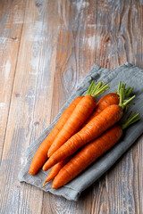 A stack of fresh carrots on country village table with kitchen towel, top view, side view