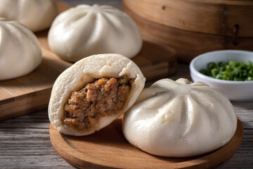 Delicious baozi, Chinese steamed meat bun is ready to eat on serving plate and steamer, close up,...