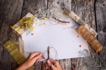 Preparing for Christmas. The girl's hands cut the ribbon for Flat lay with scissors. White blank...