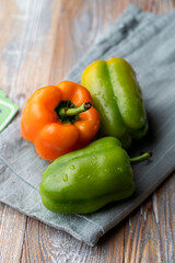 Close up view of assortment of green and orange bell peppers on country rustic tablecloth