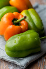 Close up view of assortment of green and orange bell peppers on country rustic tablecloth