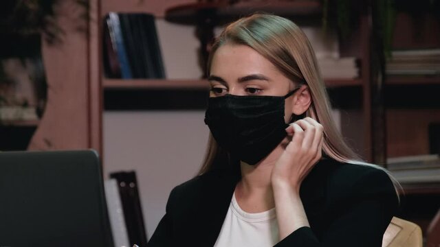 Female office worker takes off medical mask and breathe freely with full chest looking at camera. Young woman takes off virus protection. Employee is tired of the wearing mask